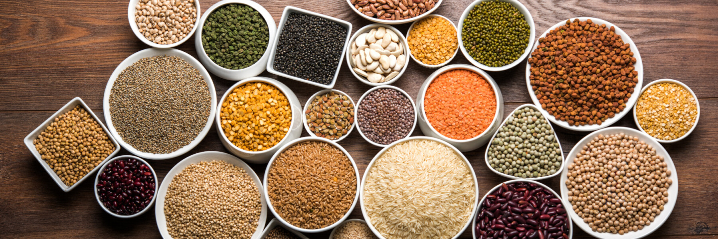 Uncooked Indian pulses, Dals, grains and seeds in White bowls over wooden background.